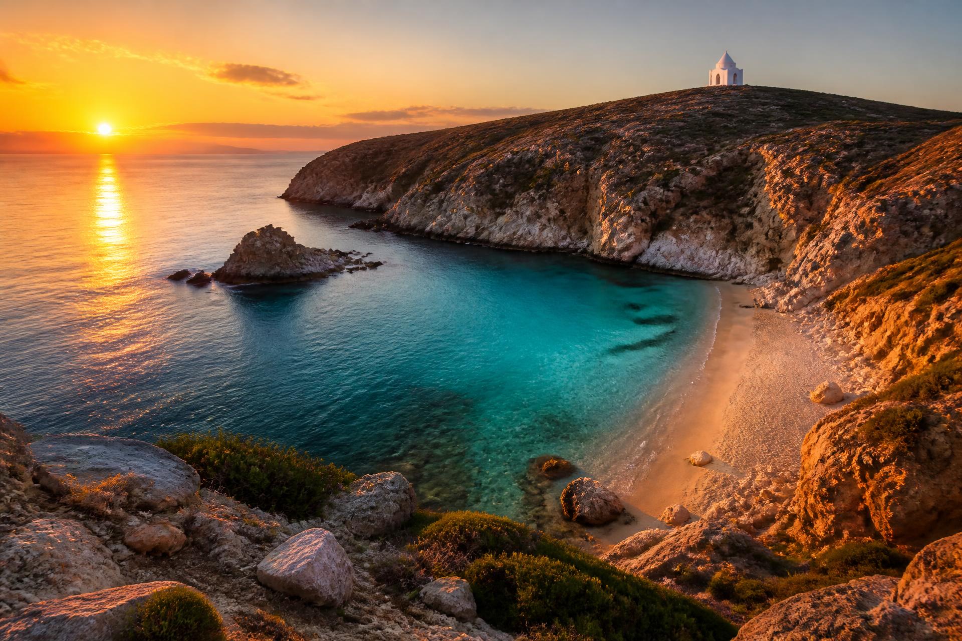 Sunset over a secluded Greek cove with a white chapel on the hilltop
